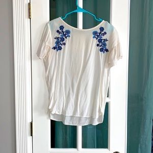 White blouse with blue flower detail.